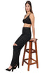 Woman wearing a black Non Padded bra and black jeans sitting on a wooden stool against a white background